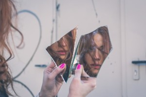 woman-looking-in-broken-mirror-TS
